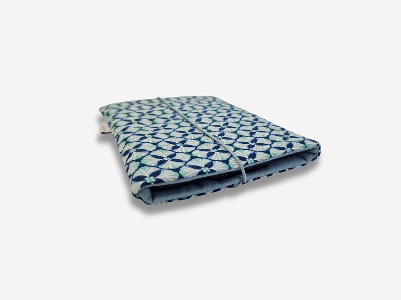 May include: A blue and white patterned fabric case with a blue elastic band closure. The case is folded closed and is lying on a white surface.