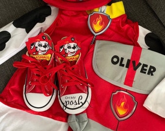 Peut inclure: Costume de Pat' Patrouille rouge et blanc avec un chapeau rouge, un sac à dos rouge et gris avec le nom "OLIVER" dessus et des baskets rouges avec un personnage de Pat' Patrouille sur chaque chaussure.