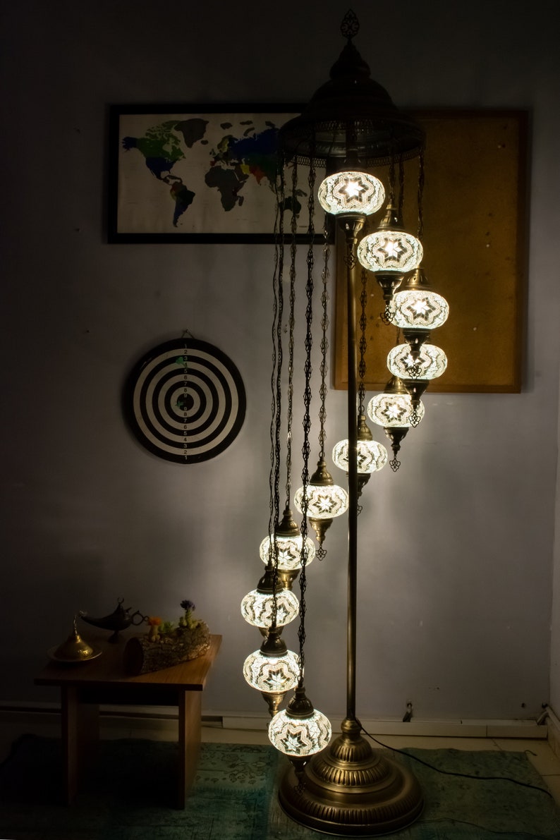 May include: A spiral floor lamp with a brass base and eight white mosaic glass globes. The lamp is lit and casting a warm glow.