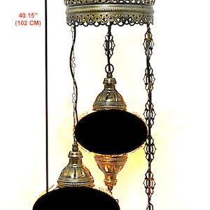 May include: A three-tiered brass chandelier with black glass shades. The chandelier is 40.15 inches (102 cm) tall and has a 13 inch (33 cm) diameter.