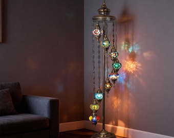 May include: A decorative floor lamp with a bronze finish and multiple colorful glass mosaic globes. The lamp has a tall, slender design with a circular base and a series of hanging globes, creating a warm and inviting ambiance. The globes are in various colors.