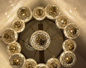 May include: A chandelier with 15 clear glass globes with intricate gold metal designs. The globes are arranged in a circle and hang from a central point.
