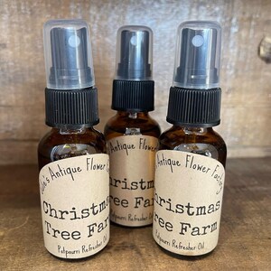 May include: Three brown glass bottles with black spray tops and labels that read "Julie's Antique Flower Factory" and "Christmas Tree Farm Potpourri Refresher Oil".