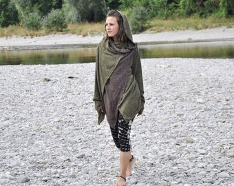 May include: An olive green hooded cardigan with long sleeves and thumb holes, layered over a dark brown tunic top. The outfit is paired with black and white tie-dye leggings that reach mid-calf, creating a layered look with textured fabric.