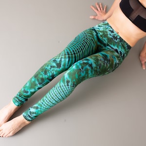 Puede incluir: Un par de leggings de color verde y azul con un estampado tie-dye ondulado.