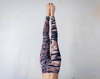 May include: Full-length leggings featuring a dark tie-dye pattern in shades of black, brown, and white. The fabric displays a repeating, organic, and abstract design that covers the entire surface of the garment from the waist down to the ankles.