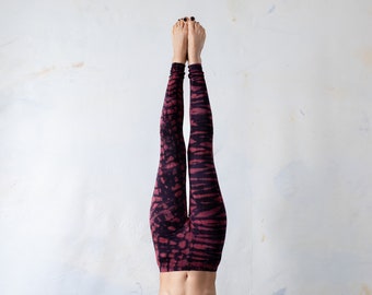May include: Full-length leggings featuring a dark burgundy and black tie-dye pattern. The fabric displays a repeating abstract design with horizontal bands of color throughout the garment, extending from the waist down to the ankles.