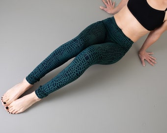 May include: High-waisted leggings featuring a dark green and black crocodile skin pattern. The leggings are form-fitting, extending from the waist down to the ankles, with a consistent scale-like texture throughout the fabric design.