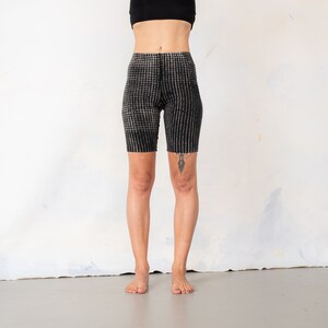 May include: High-waisted biker shorts featuring a black and white checkered pattern. The shorts have a fitted silhouette that extends to the mid-thigh, constructed with a textured fabric that displays a consistent grid design across the entire garment.
