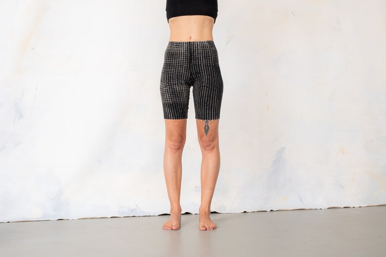 May include: High-waisted biker shorts featuring a black and white checkered pattern. The shorts have a fitted silhouette that extends to the mid-thigh, constructed with a textured fabric that displays a consistent grid design across the entire garment.