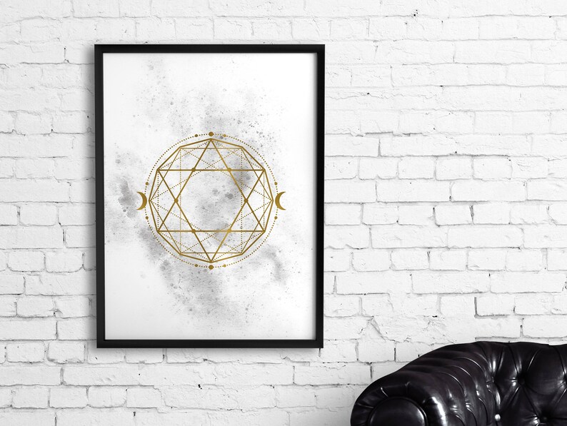 May include: A black framed print with a white background and a gold geometric design. The design is a circle with a star inside and a crescent moon on each side. The background is a watercolor wash of gray and white.
