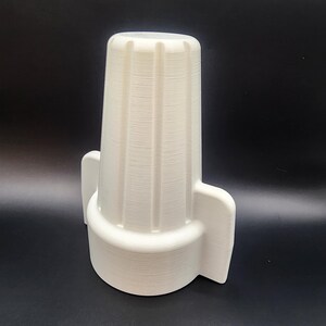 May include: White plastic electrical outlet cover with a ribbed design. The cover has two side tabs for easy installation.