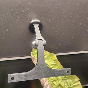 Puede incluir: Soporte de pared de metal negro con una base redonda y un brazo articulado. El soporte est&aacute; fijado a la pared con un tornillo. El brazo est&aacute; extendido y tiene una placa plana rectangular en el extremo.