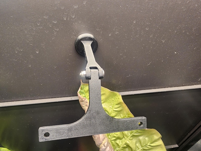 Puede incluir: Soporte de pared de metal negro con una base redonda y un brazo articulado. El soporte est&aacute; fijado a la pared con un tornillo. El brazo est&aacute; extendido y tiene una placa plana rectangular en el extremo.