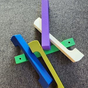 May include: Five wooden handles in different colors: purple, white, green, blue, and yellow. The handles have a cutout design and are arranged in a crisscross pattern.