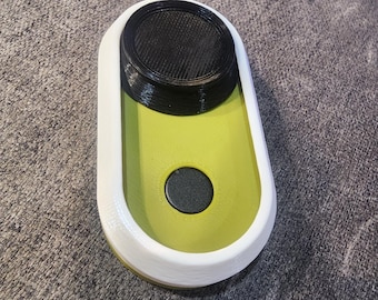 May include: A small, oval-shaped, green and white device with a black button and a black circular top.