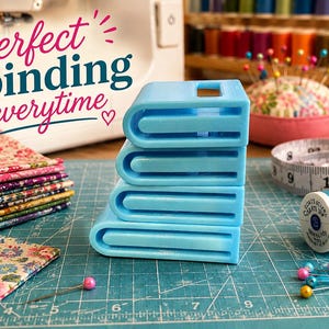 May include: A stack of four light blue plastic bias tape makers of varying sizes. The text "Perfect binding everytime" is visible in the upper left corner. The tools are positioned on a green cutting mat with sewing supplies nearby.