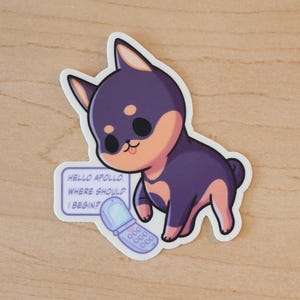 Può includere: Un adesivo raffigurante un cane dei cartoni animati con pelo viola e marrone chiaro, una lingua rosa e grandi occhi neri. L'adesivo include un piccolo cartello con il testo "HELLO APOLLO. WHERE SHOULD I BEGIN?" e un telefono a conchiglia.