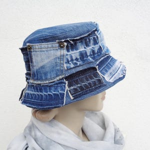 Op de afbeelding: Een blauwe denim bucket hat gemaakt van hergebruikt denim. De hoed heeft een brede rand en is versierd met patches van verschillende denim stoffen.
