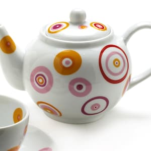 May include: White teapot with a colorful polka dot pattern in shades of pink, orange, and red. The teapot has a round body and a curved spout.