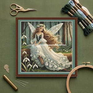 May include: A framed cross-stitch of a fairy in a forest setting. The fairy has long, flowing hair, a white dress, and delicate wings. The image is surrounded by embroidery supplies, including scissors, needles, and thread.