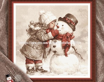 May include: A PDF digital download cross stitch pattern featuring a sepia-toned illustration of a child in a winter coat and hat kissing a snowman wearing a dark hat and red scarf. The design includes the text PDF Digital Download Cross Stitch Pattern.
