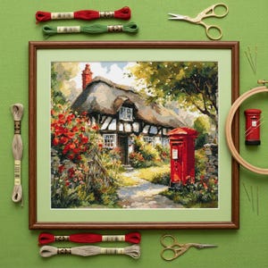 May include: Framed cross-stitch art depicting a quaint cottage with a thatched roof, red flowers, and a red mailbox. The artwork is surrounded by embroidery floss, scissors, needles, and a wooden hoop, all on a green background.