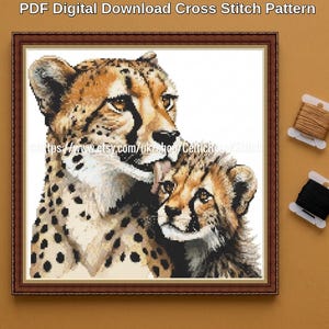 Puede incluir: Un patrón de punto de cruz que muestra a un guepardo adulto acicalando a su cría, en tonos beige, negro y blanco. La imagen enmarcada incluye el texto PDF Digital Download Cross Stitch Pattern y dos pequeñas bobinas de hilo de bordar marrón y negro.