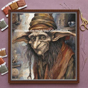 Puede incluir: Un bordado de punto de cruz enmarcado de una criatura fantástica con una nariz larga, orejas grandes y una sonrisa traviesa. La criatura lleva un sombrero y abrigo marrones. El fondo representa un paisaje urbano detallado y envejecido. El texto "https://www.etsy.com/uk/shop/CelticRoseXStitch" es visible.