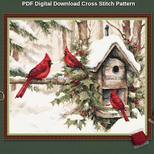 May include: A PDF digital download cross stitch pattern featuring a winter scene with three bright red cardinal birds, a wooden birdhouse covered in snow, green pine branches, and red berries. Gold scissors and two spools of thread are visible.