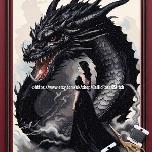 Può includere: Uno schema a punto croce con un grande drago nero dagli occhi rossi che sovrasta una figura con un lungo abito nero. Il testo recita PDF Digital Download Cross Stitch Pattern e https://www.etsy.com/uk/shop/CelticRoseXStitch. Sono incluse forbici dorate e filo nero.