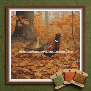 May include: Framed cross-stitch of two pheasants in a forest setting with autumn leaves. The male pheasant has vibrant red, brown, and black plumage. The artwork is framed in a brown wooden frame. The text "https://www.etsy.com/uk/shop/CelticRoseXStitch" is visible.