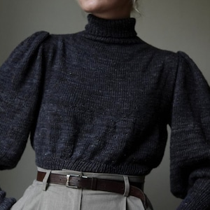 May include: A dark gray turtleneck sweater with puffed sleeves and a brown leather belt. The sweater is made of a soft, textured fabric.