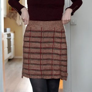May include: A brown and red plaid skirt with a knitted texture. The skirt is knee-length and has a straight silhouette.