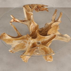May include: A round coffee table featuring a clear glass top supported by a natural light brown wooden tree root base. The base displays organic, branching wood textures and knots, providing a stable foundation for the circular glass surface.
