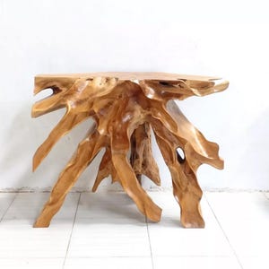 May include: A natural wood console table with a unique root-like base. The table has a smooth, light brown tabletop and a complex, textured base with multiple root-like supports. The overall design is organic and sculptural, suitable for a living room or entryway.