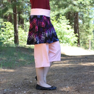 Skirted leggings (a skirt is attached to the bottom of the waistband, much like a skort).  Waistband and leggings are pale pink.  Skirt is black with pink and purple designs in a rough diamond pattern.