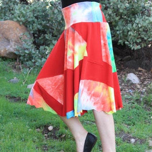 May include: A red, white, and blue tie-dye skirt with a patchwork design. The skirt is made of a soft, stretchy fabric and has a flowy silhouette.