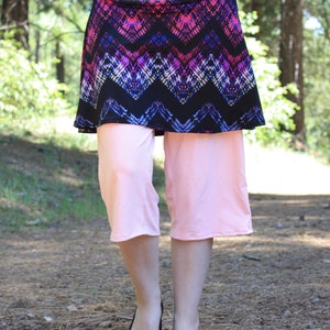 Front view showing diamond/triangular pattern in skirt fabric.  The leggings are slightly loose, and reach a little past the model's knees.
