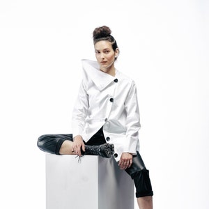 Sculptural avant-garde cotton shirt with asymmetric cuts and contrasting black buttons