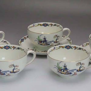 May include: Set of four teacups and saucers with a blue and white floral pattern. The cups and saucers feature a delicate floral design with a gold trim.