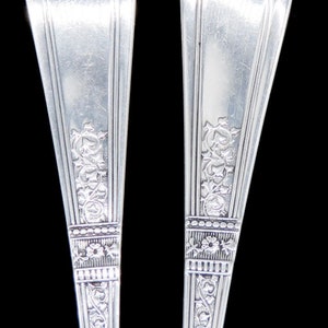 May include: Two silver-plated spoons with ornate floral designs on the handles. The spoons have a classic, elegant style.