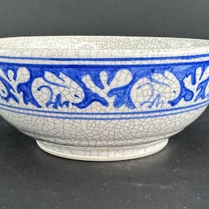 Könnte beinhalten: Eine weiße Keramikschüssel mit einem blauen und weißen Blumendesign. Die Schüssel hat eine craquelée Glasur und ist perfekt zum Servieren von Salaten, Obst oder anderen Gerichten.
