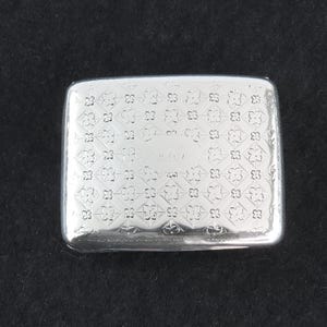 May include: A silver cigarette case with a decorative pattern and the number "410" engraved on the front.