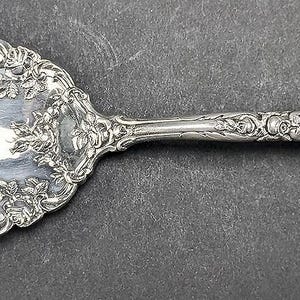 May include: A silver fork with an ornate handle featuring a floral design. The fork has four tines and is in good condition.