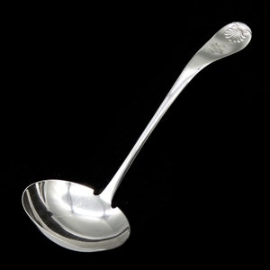 May include: A silver ladle with a decorative handle. The handle has a floral design and a raised letter "S".