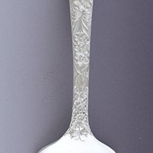 Puede incluir: Un tenedor de plata con un diseño floral ornamentado en el mango. El tenedor tiene cuatro dientes y está hecho de plata pulida.