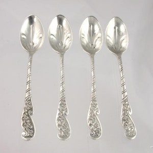 Puede incluir: Juego de cuatro cucharaditas de plata con diseños florales ornamentados en los mangos. Las cucharas tienen un tallo retorcido y un cuenco redondeado.