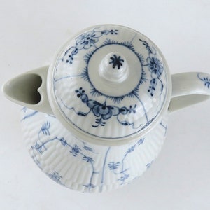 May include: A white ceramic teapot with a blue and white floral pattern. The teapot has a lid with a knob on top and a spout on the side. The teapot is decorated with a blue and white floral pattern.