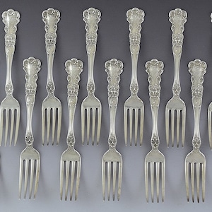 May include: Set of twelve silver forks with ornate handles. The forks have a traditional design with a rounded, fluted handle and three tines.